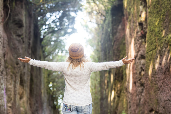 happiness-and-joyful-freedom-concept A woman with her arms up as if she's celebrating life and having broken free of addictions that were holding her back.